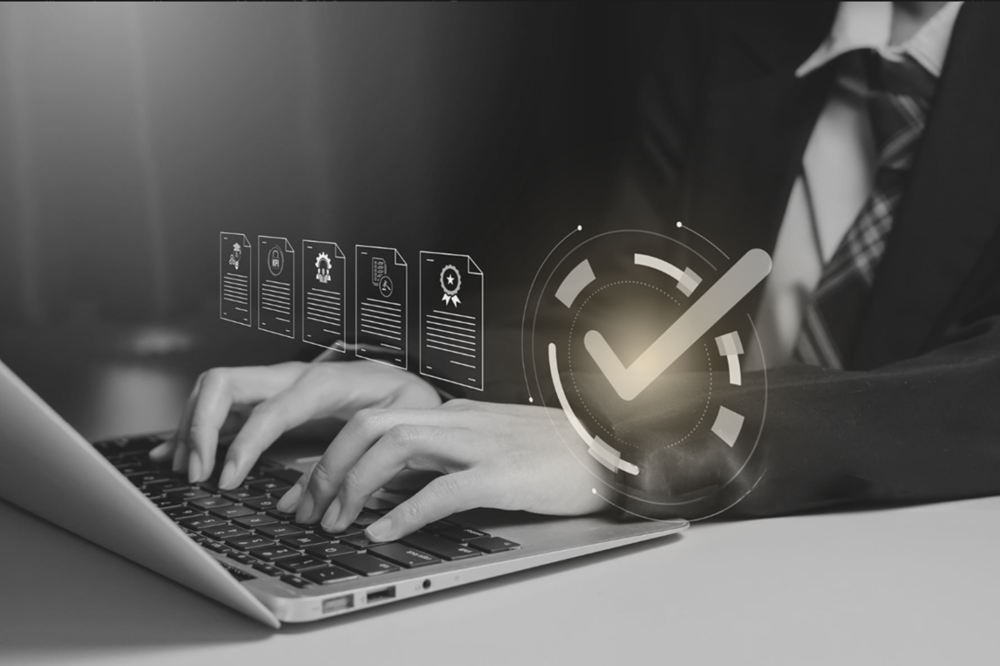 Businessperson typing on a laptop with a glowing checkmark and floating document icons to symbolize digital verification/approval in progress